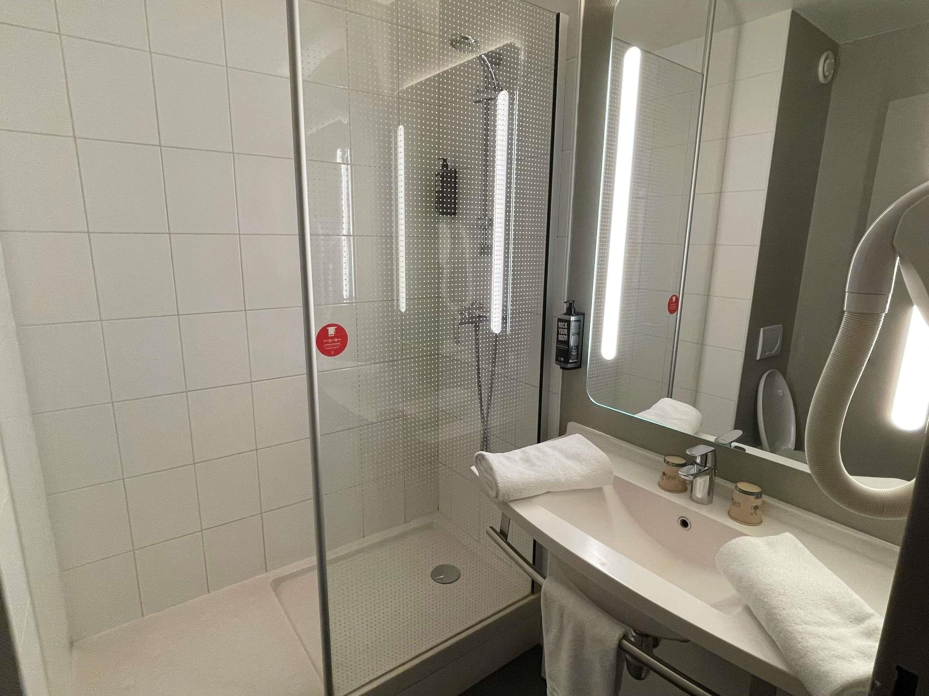 A modern bathroom with a glass shower enclosure, a white sink with a mirror, and a handheld showerhead.