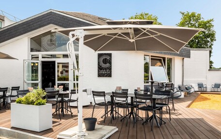 An outdoor seating area with tables and chairs, a large umbrella, and a sign reading "CHARLIE'S CORNER".