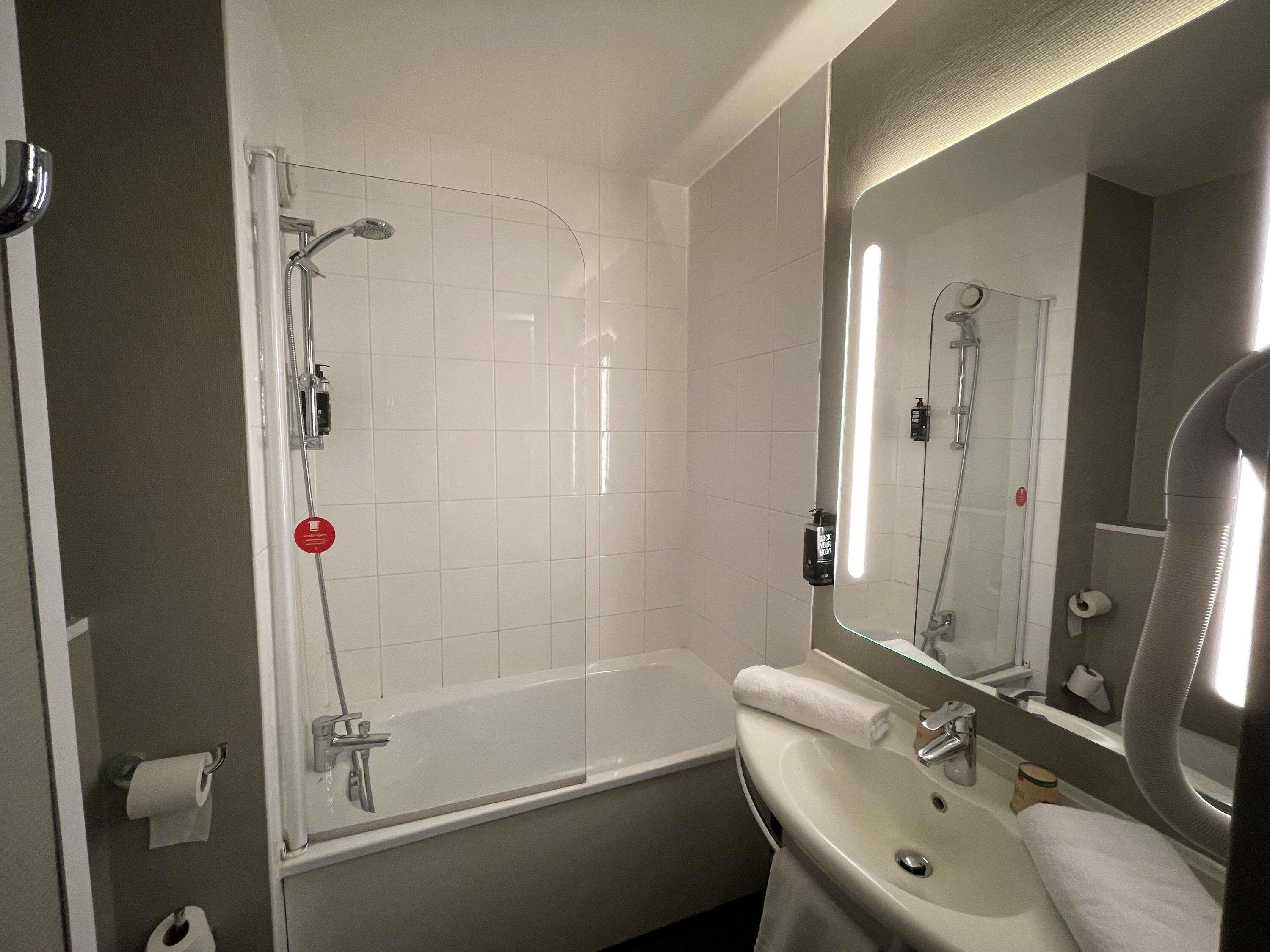 A modern bathroom with a glass-enclosed shower, a white sink, and a large mirror.
