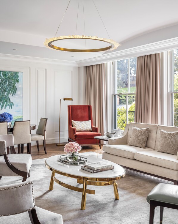 Una sala de estar moderna con un sillón rojo, sofá beige y una mesa de centro redonda con un jarrón de flores.