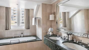 A modern bathroom with two sinks, a large mirror, and a window with curtains.