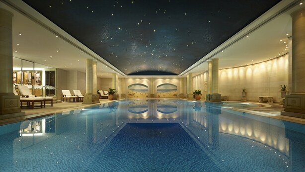 Una amplia piscina cubierta con techo estrellado, sillones de descanso y zona de spa.