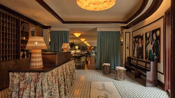 Un vestíbulo de hotel con piso a cuadros, una recepción y una zona de bar.