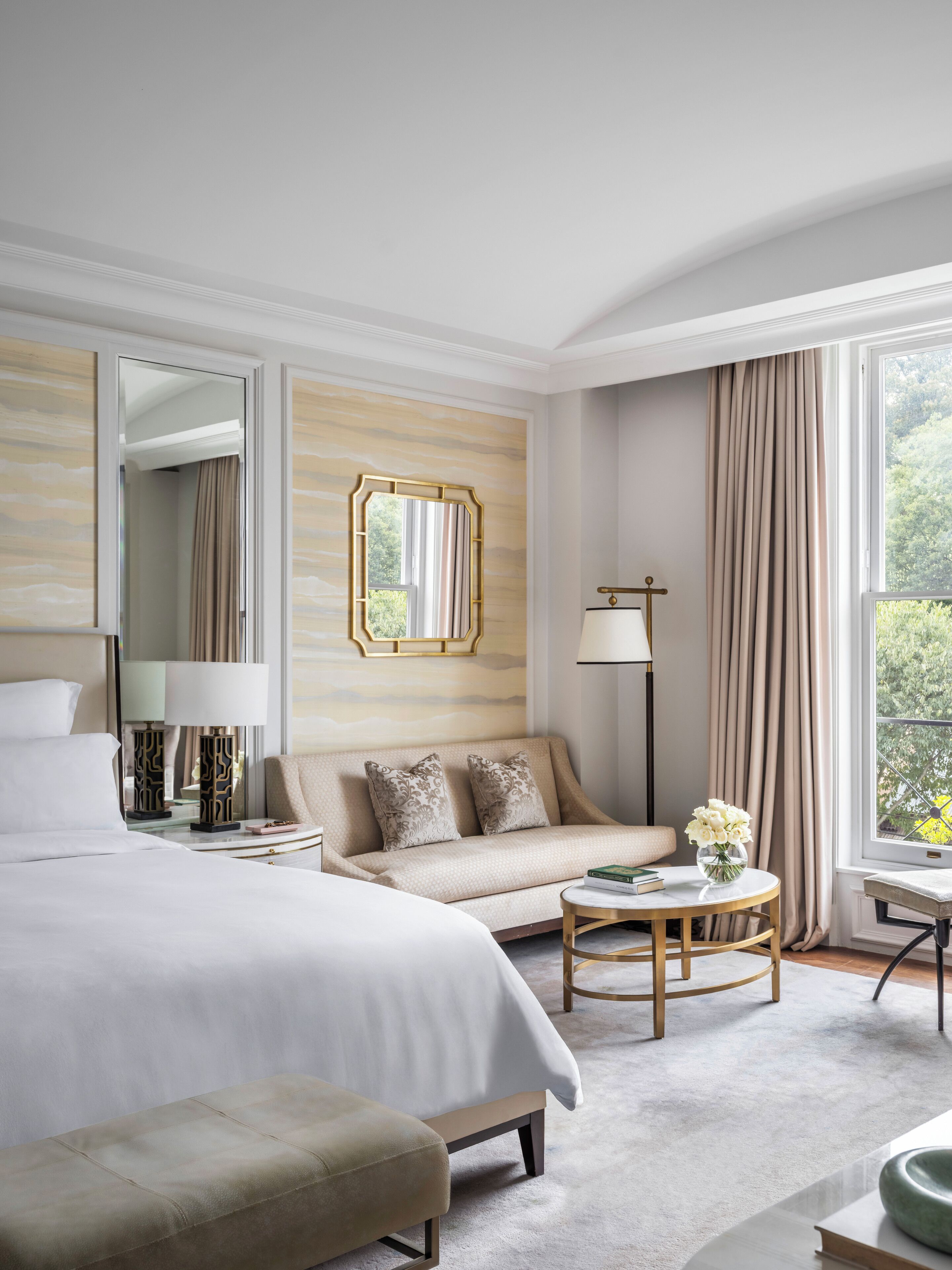 Une chambre d’hôtel avec un grand lit, un canapé, une petite table et une fenêtre avec des rideaux.