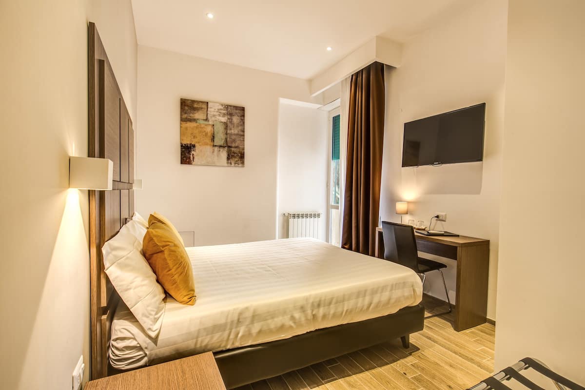 A modern bedroom with a bed, bedside table, and a desk with a chair.