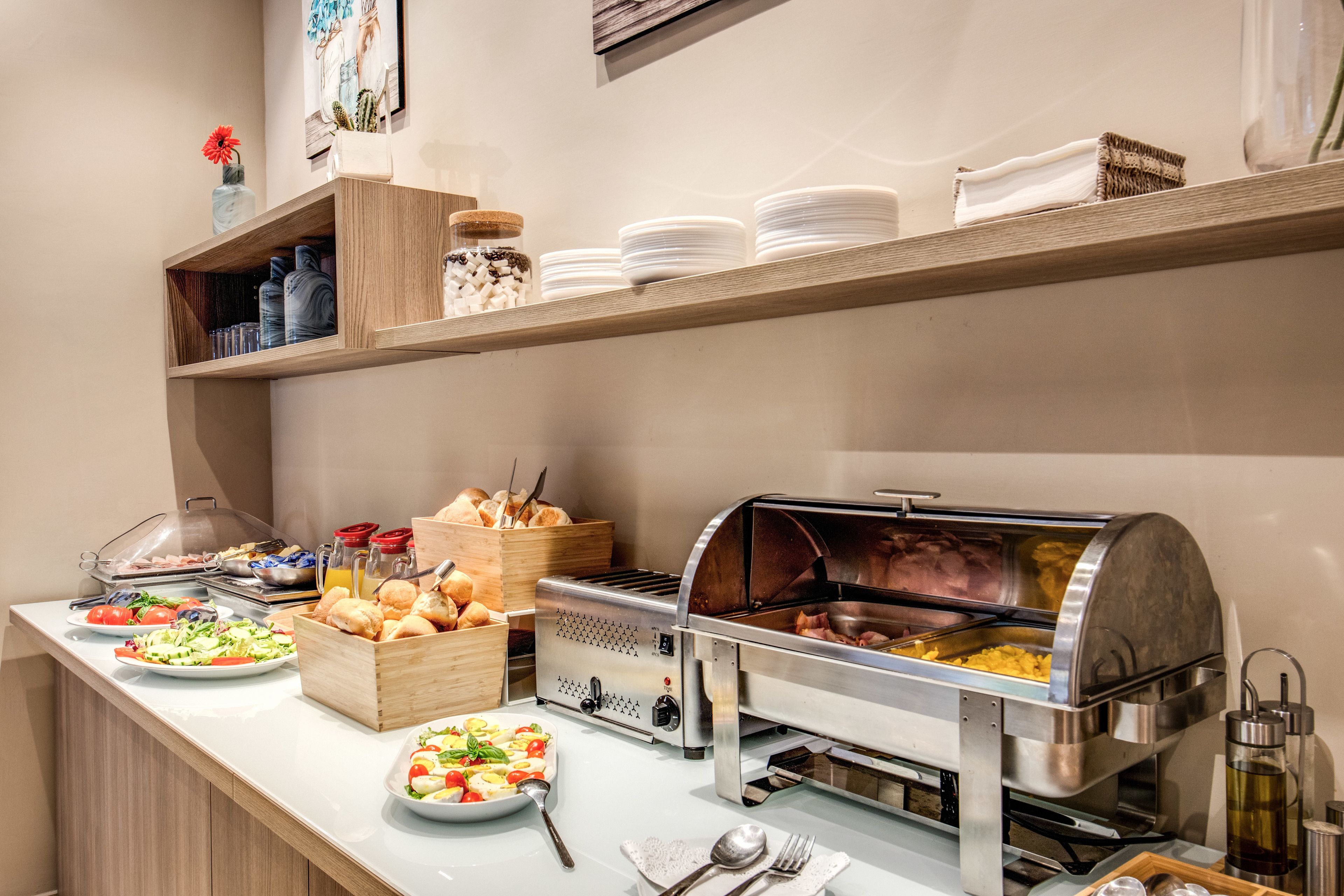 Un buffet proposant une variété de plats, un barbecue où l’on peut se servir soi-même, ainsi que des assiettes et des bols disposés avec soin.