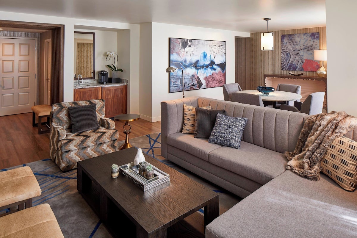 A modern living room with a sofa, armchairs, a coffee table, and a dining area.