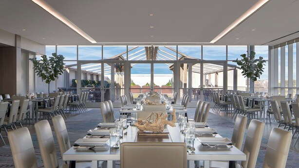 A spacious dining area with long tables, chairs, and a central decorative sculpture. - Renaissance Dallas Hotel (Dallas)