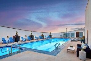 Una piscina al aire libre, sombrillas, sillones reclinables de piscina