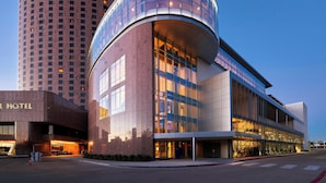 A modern hotel with a curved glass facade, a prominent entrance, and a parking area. - Renaissance Dallas Hotel (Dallas)