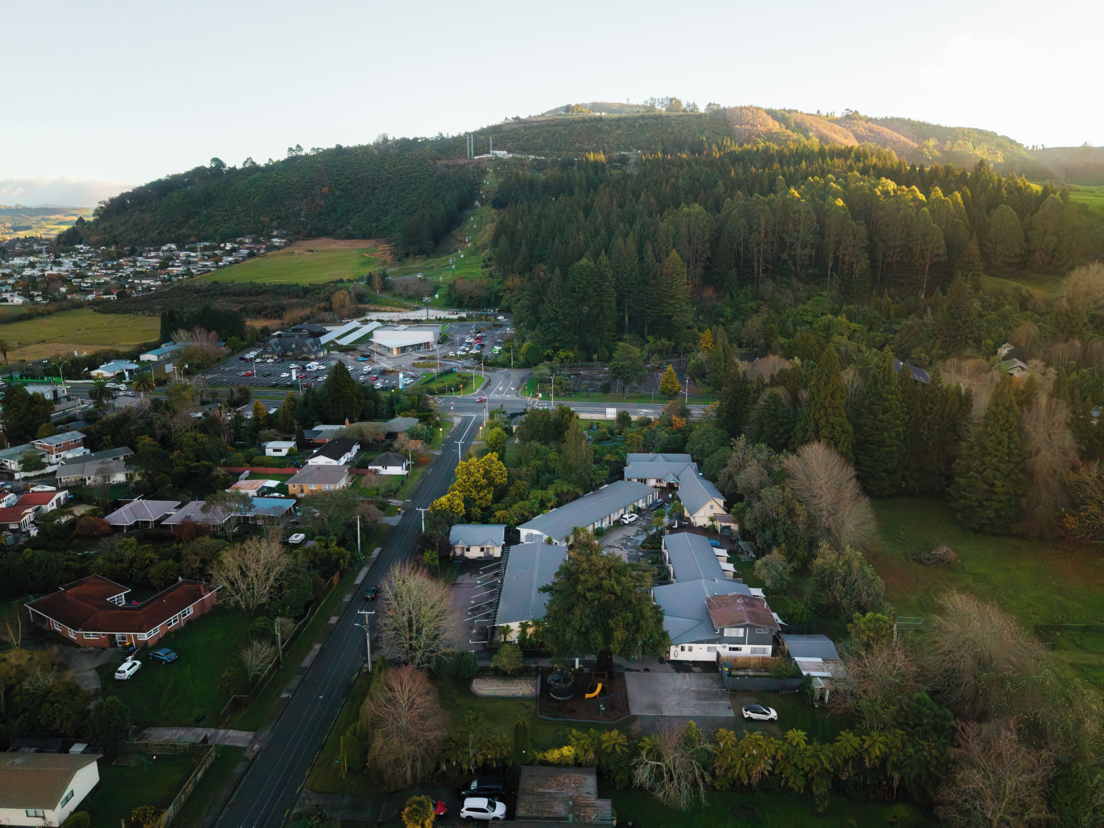 Vista aérea de una zona residencial con casas, calles y una colina al fondo.