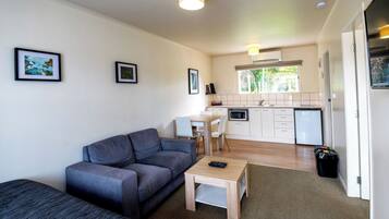 A compact living space with a sofa, a small table, a kitchen area with a microwave, and a dining table.