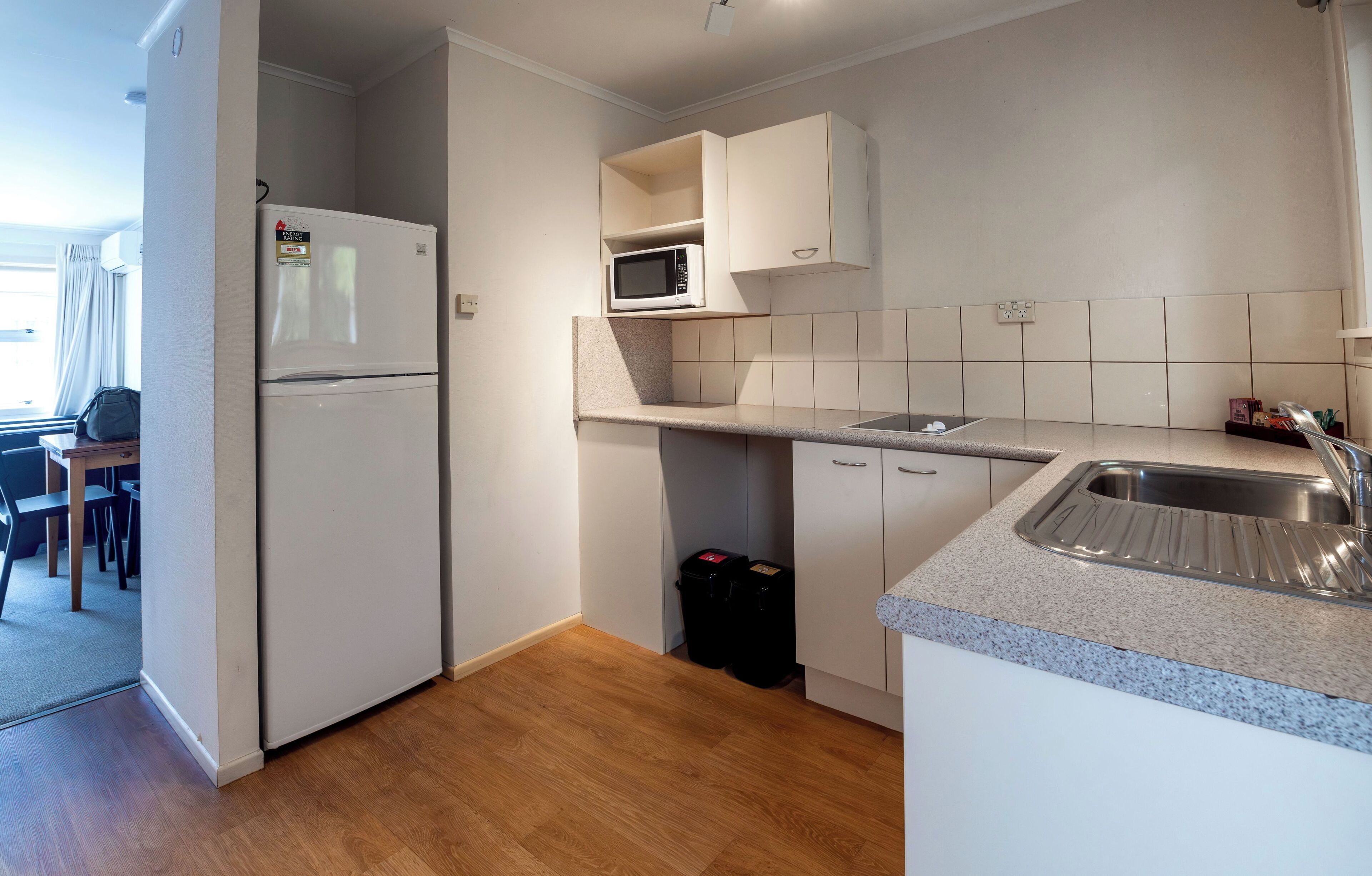 Una cocina compacta con microondas integrado, pileta de acero inoxidable y refrigerador.