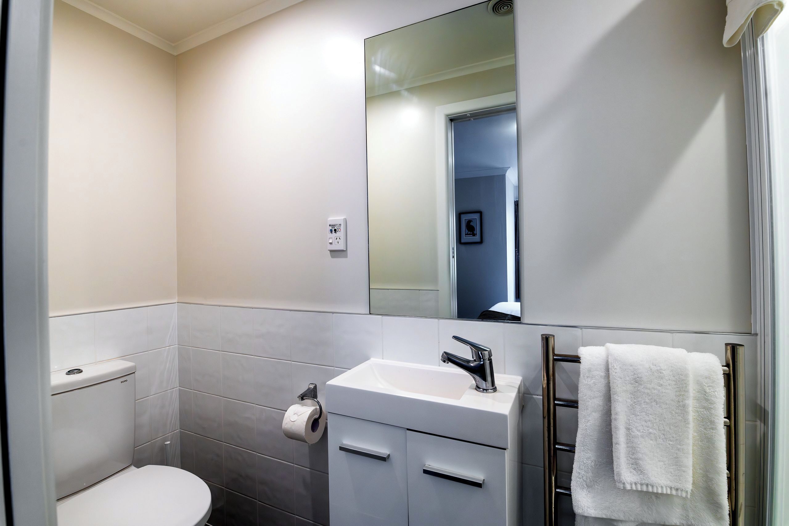 Une salle de bain moderne équipée de toilettes, d’un lavabo et d’un porte-serviettes.