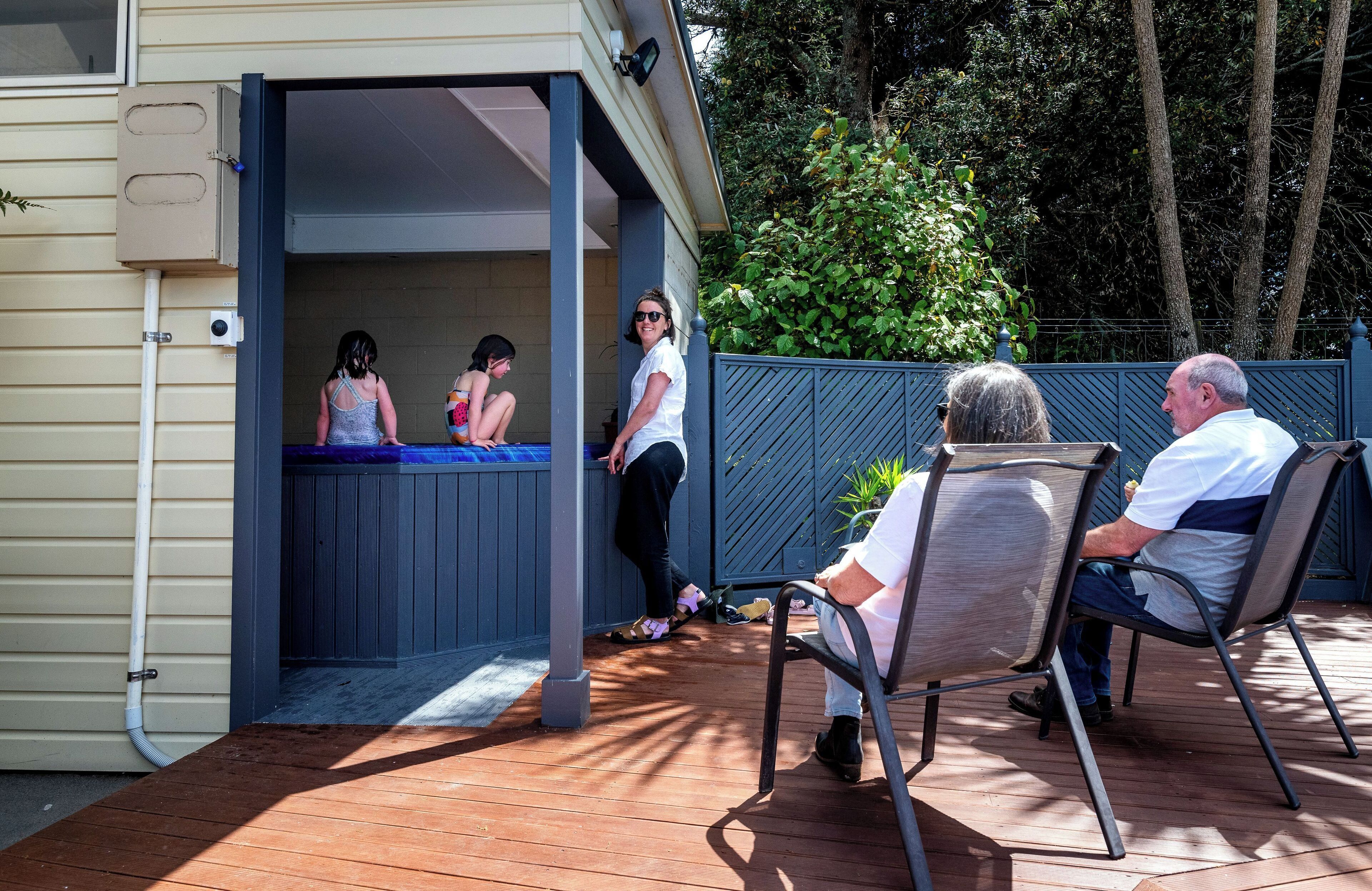 An outdoor deck with a pool area, a covered seating area, and a wooden deck.