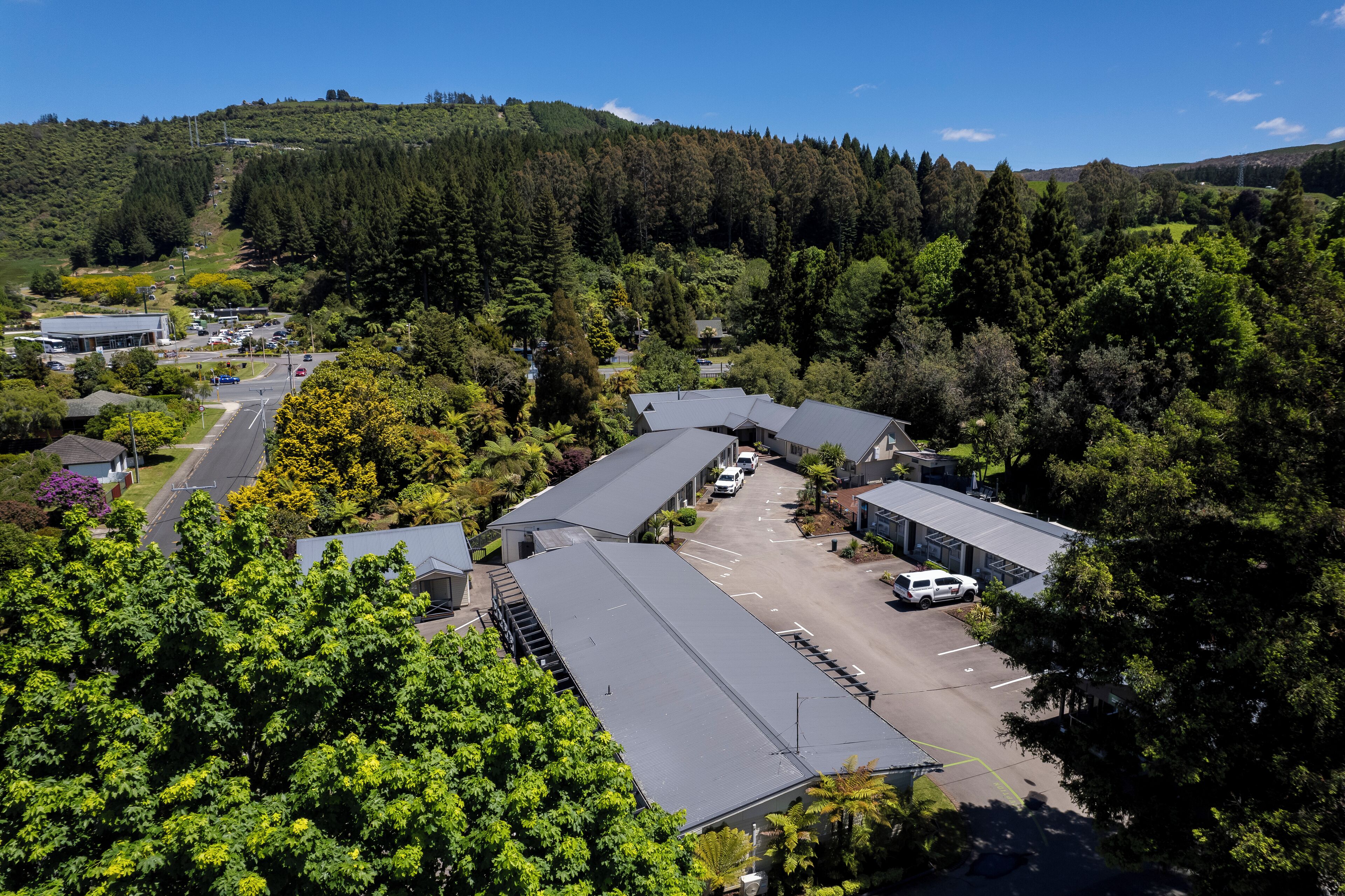 A commercial building with multiple parking spaces and a road leading up a hill.