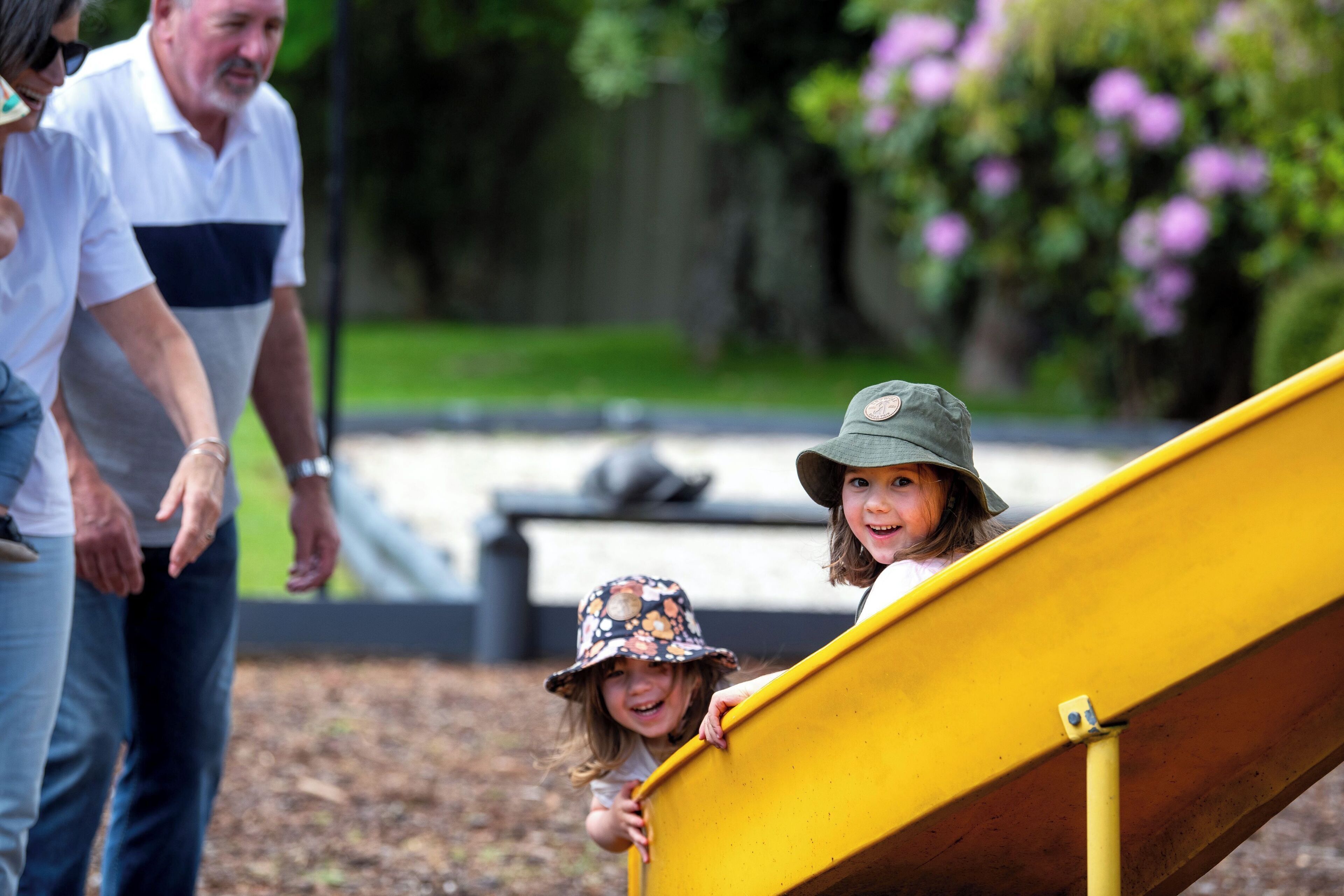A playground with a yellow slide and a child climbing up.