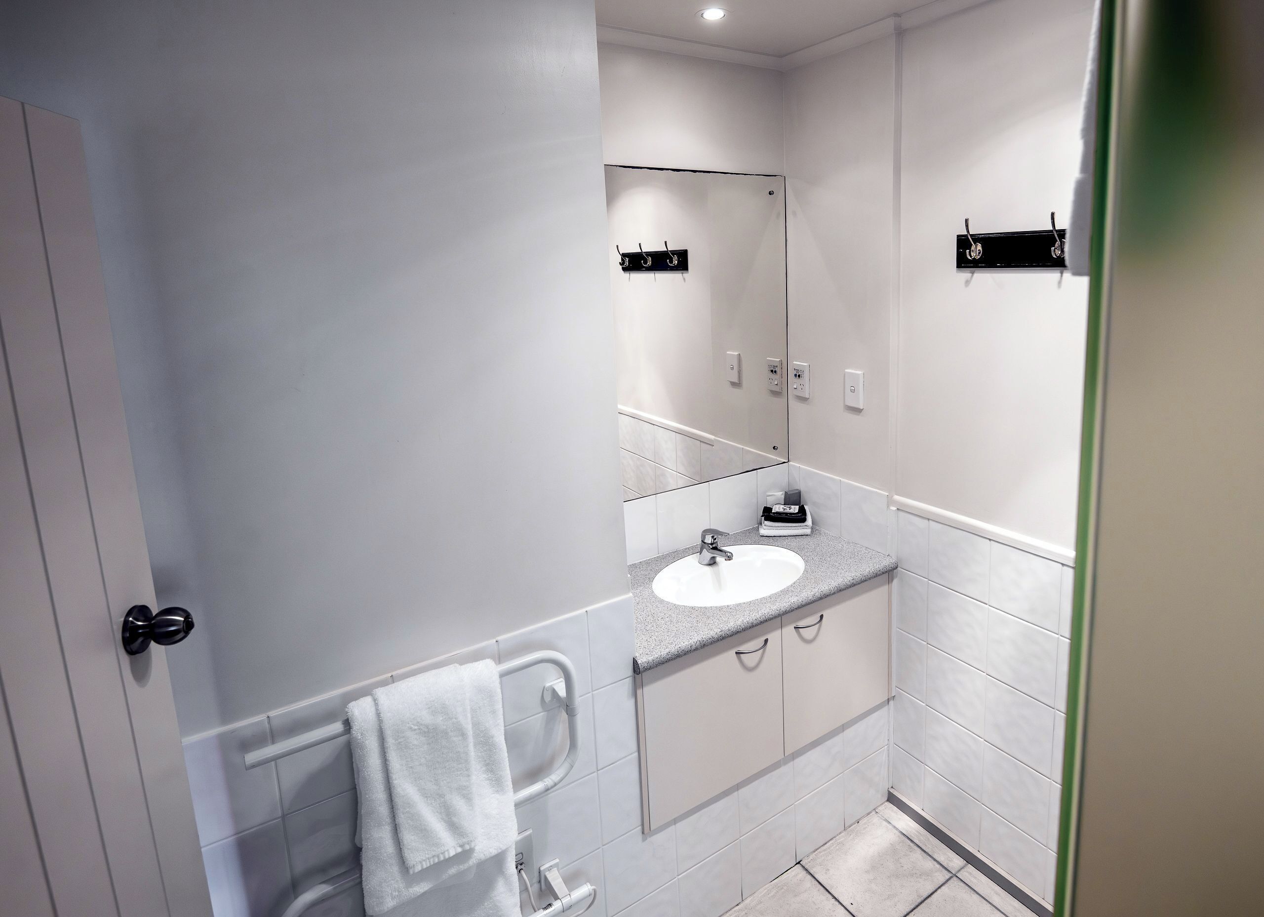 A modern bathroom with a white sink, a towel rack, and a mirror.
