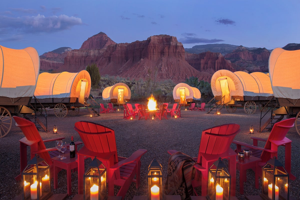A campsite with red chairs and tents, a fire pit, and lanterns.