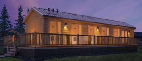 A wooden building with a covered deck and multiple doors, likely a lodge or cabin.