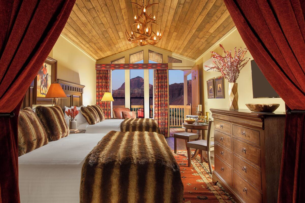 A spacious room with a large bed, a wooden ceiling, and a view of mountains through the window.