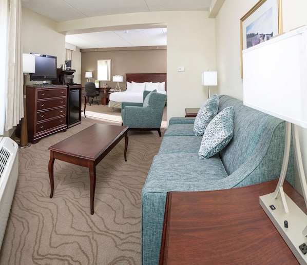 Una habitación de hotel con cama, sofá, escritorio, televisor y cómoda.