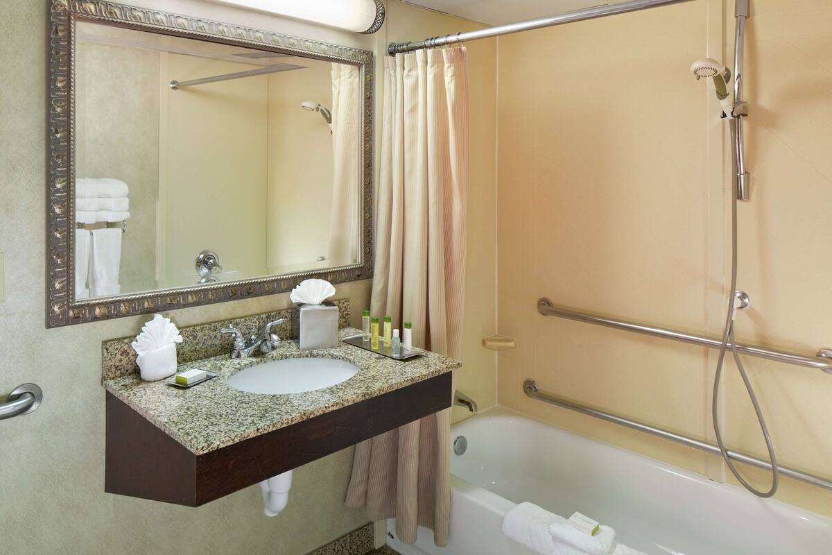 A bathroom with a sink, mirror, shower, and bathtub.