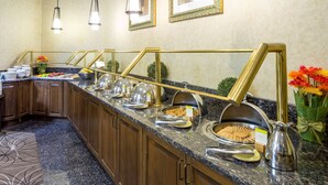 A buffet setup with various food items and a syrup dispenser. - DoubleTree by Hilton Boston - Milford (Milford)