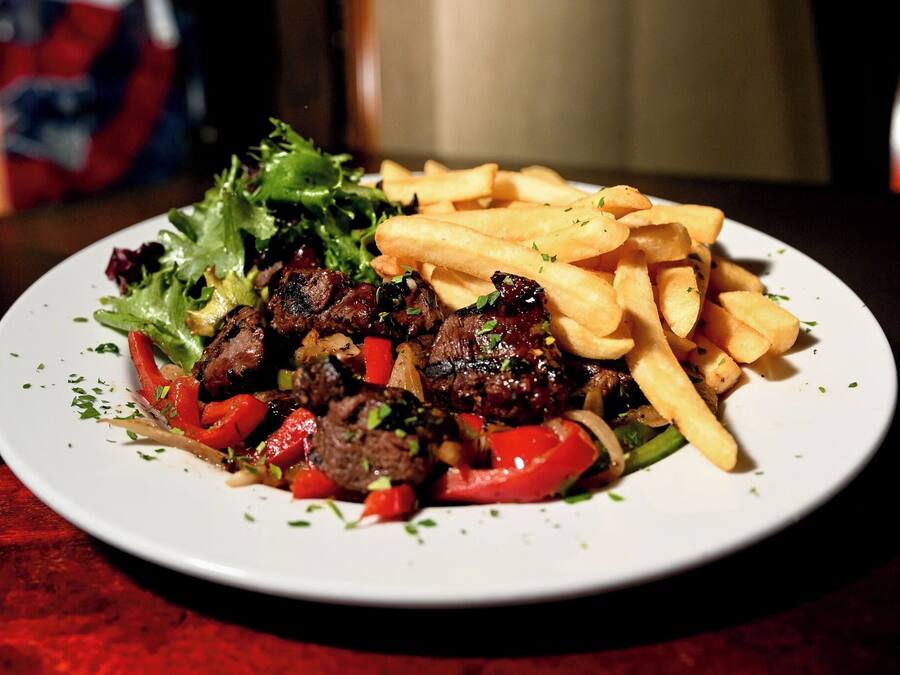 Une assiette contenant de la viande, des légumes et des frites.