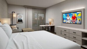 A hotel room with a large bed, a desk with a laptop, a TV, and a window with curtains. - DoubleTree by Hilton Boston - Milford (Milford)
