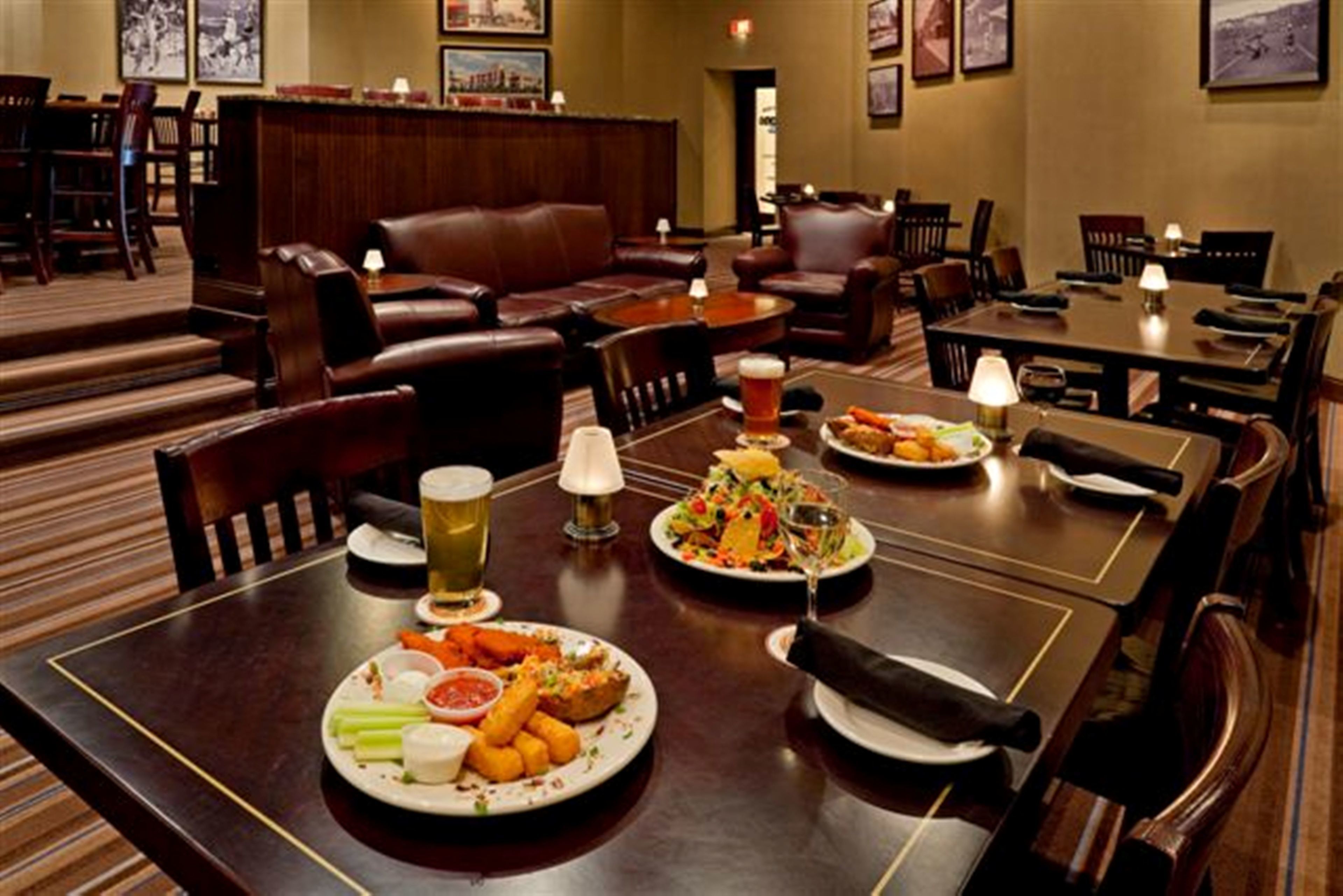 A restaurant with wooden tables, leather seating, and a variety of dishes including salads, seafood, and appetizers.