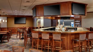 Eine Bar mit Holzwegen, einem großen Bildschirm und einer Minibar.
