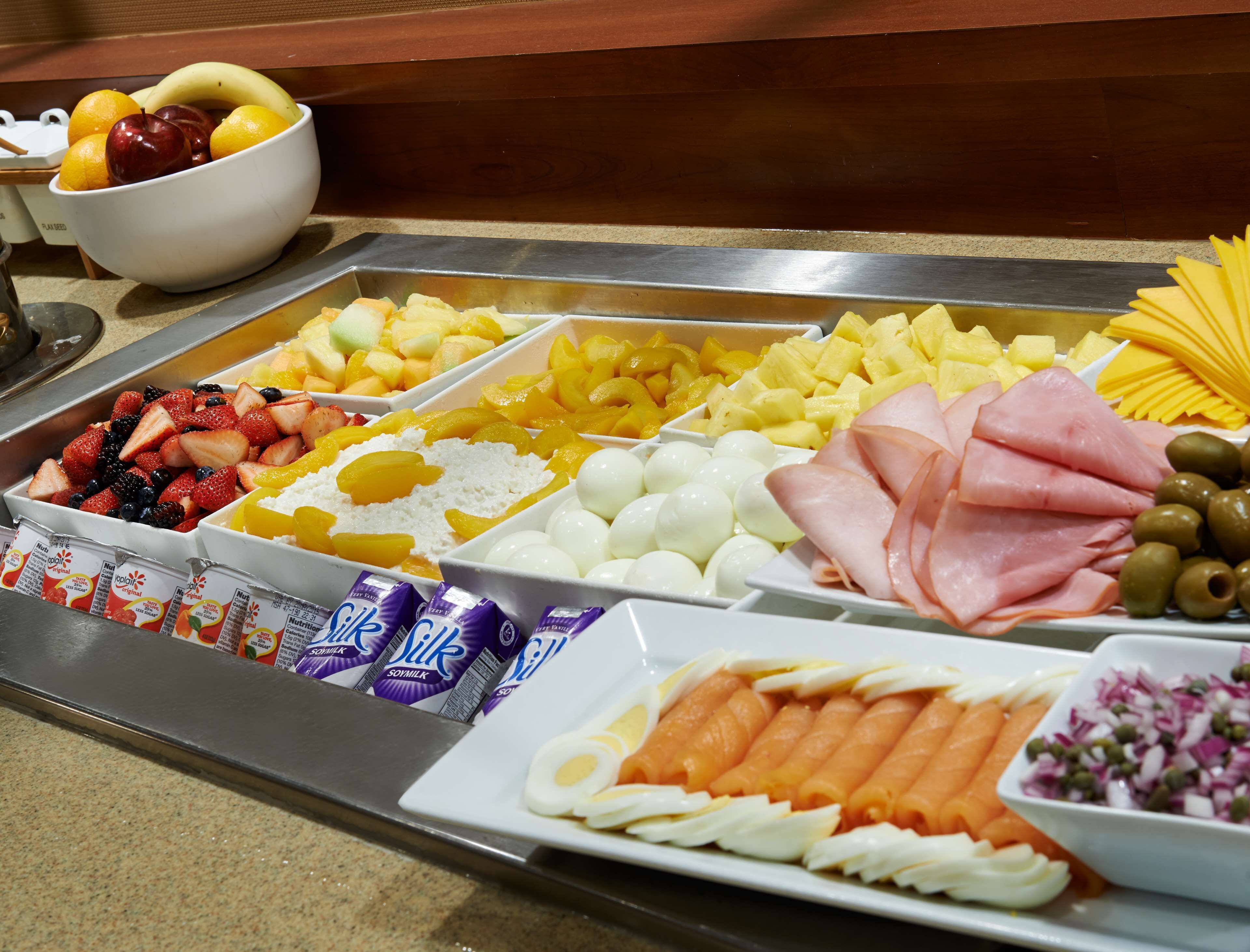 Een buffet met diverse etenswaren, zoals fruit, kazen, vlees en eieren.
