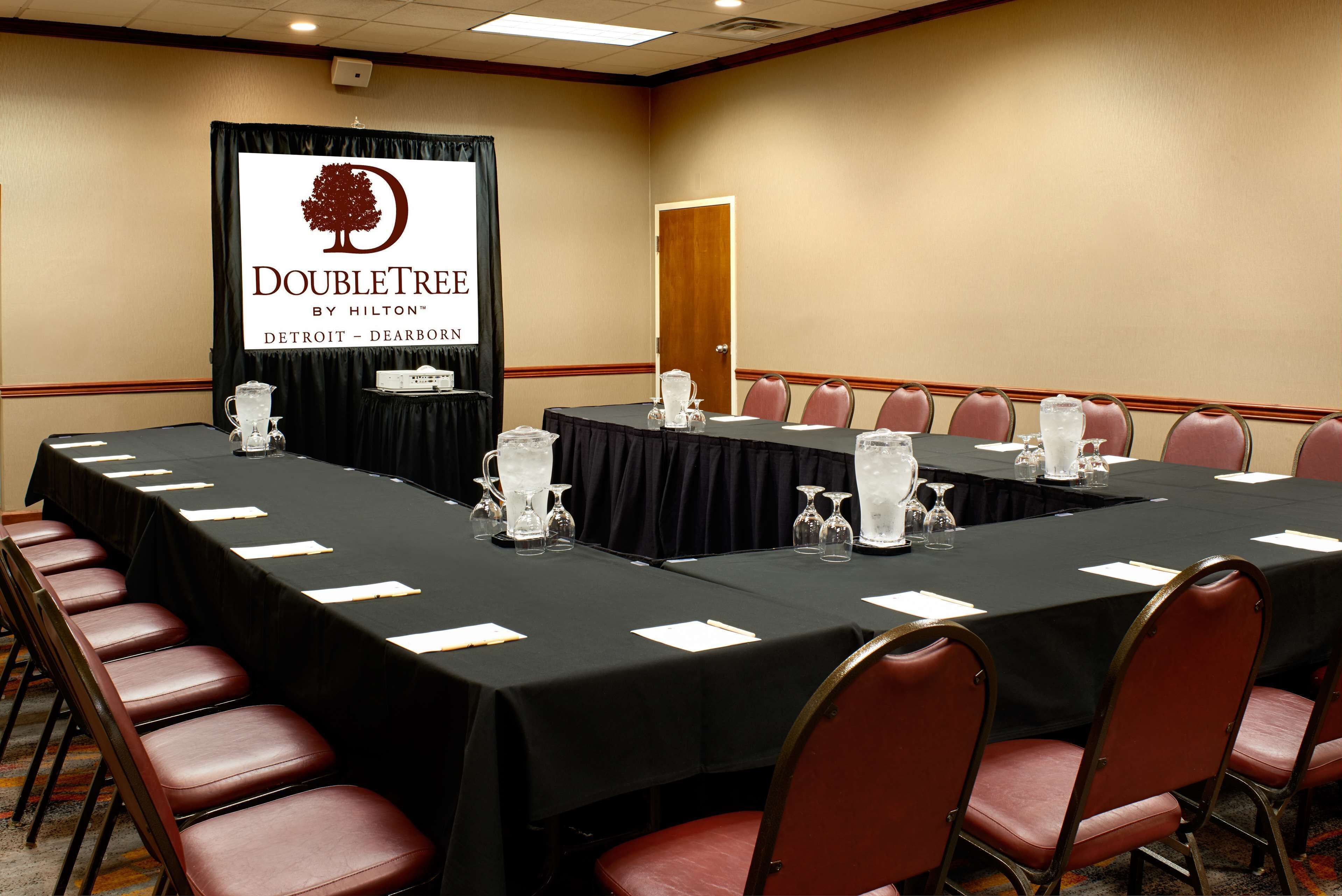 Une salle de conférence avec une longue table, des chaises et une banderole.