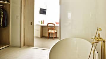 Une salle de bain avec une baignoire, une chaise en bois et un bureau avec une chaise.