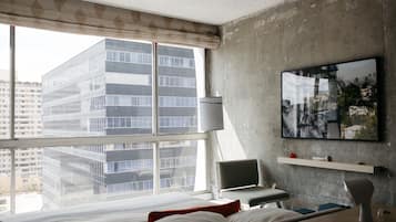 Une chambre d’hôtel moderne dotée d’une grande fenêtre, d’un lit, d’un bureau, d’une chaise et d’une œuvre d’art accrochée au mur.