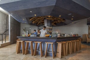 A bar area with a central counter, stools, and a bartender.