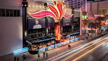 Un restaurant Gordon Ramsay Burger avec une grande enseigne lumineuse, des tables en terrasse et une vue sur la rue.