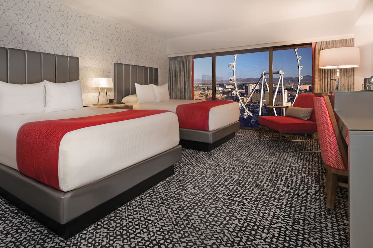 A hotel room with two beds, a red and white color scheme, a city view, and a patterned carpet.