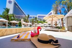 A poolside area with lounge chairs, umbrellas, and a flamingo float.