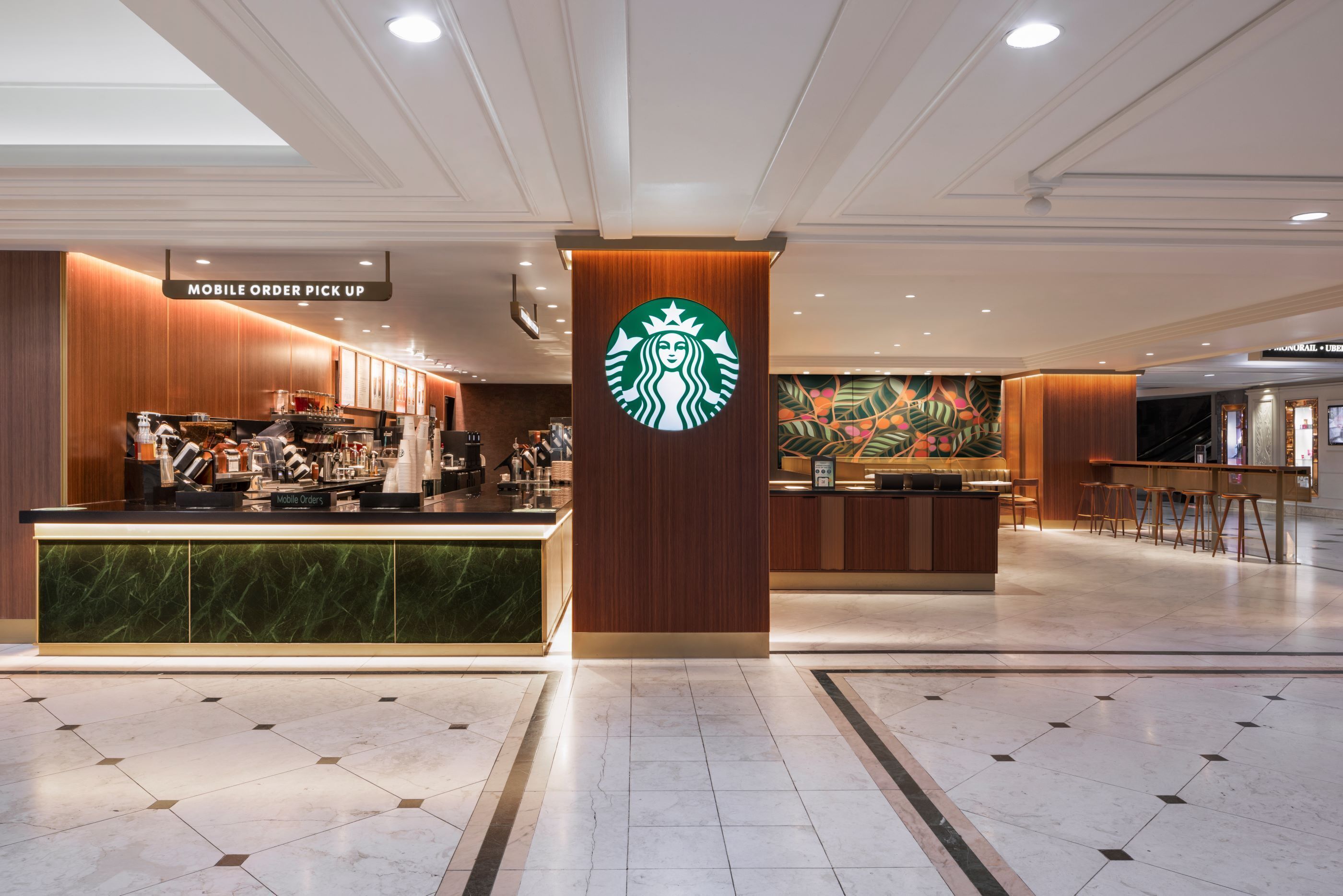 A Starbucks coffee shop with a mobile order pick-up counter and a mural on the wall.