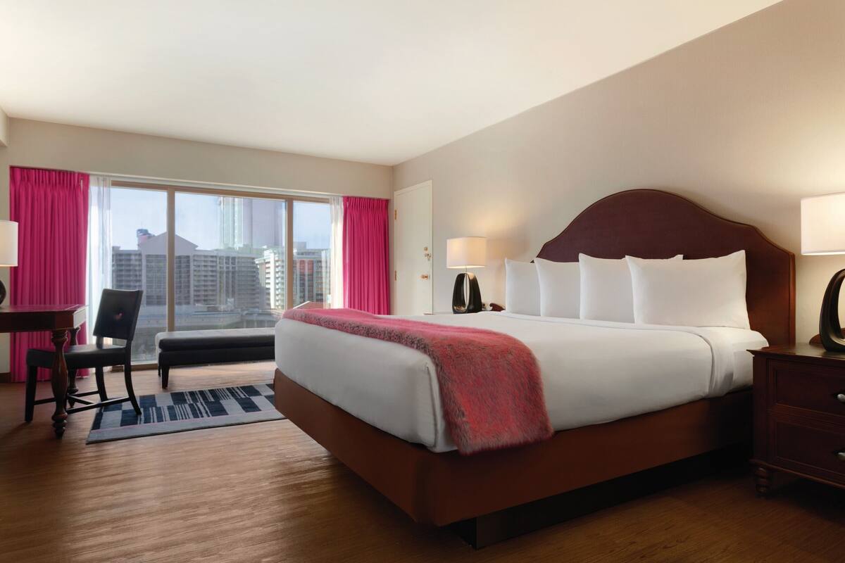 A hotel room with a large bed, a desk, and a chair.