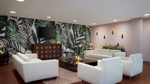 A modern living room with white sofas, a coffee table, and a wall-mounted TV.
