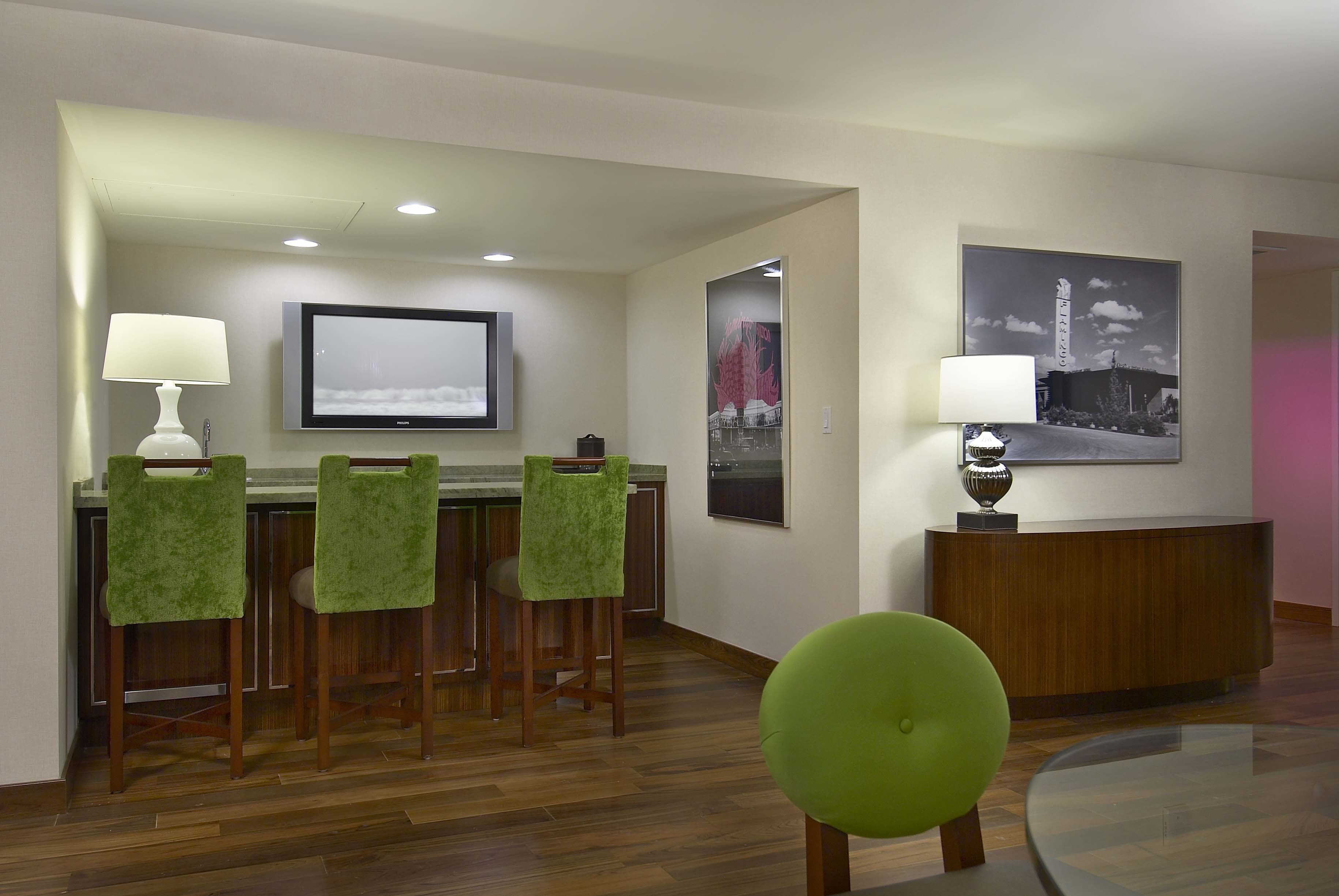 Een hotellobby met een bar, een receptiebalie en een aan de muur bevestigde televisie.