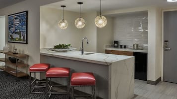 Una cucina moderna con un piano di lavoro in marmo, un lavello, una macchina per caffè e tre lampade a sospensione.