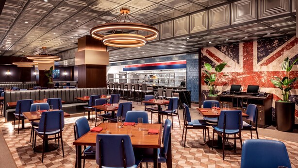 Un restaurante con cabinas y mesas, una zona de bar y una pared con diseño de la bandera Union Jack.