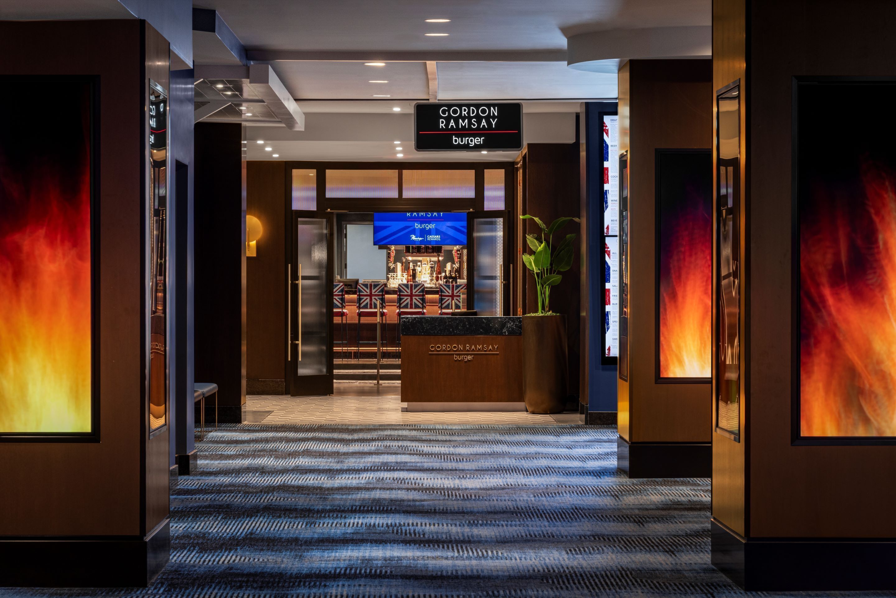 A hotel lobby with a reception desk, a sign for Gordon Ramsay Burger, and a bar area.