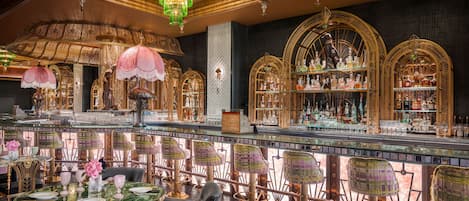 A bar area with ornate chandeliers, glass display cases, and a variety of seating arrangements.