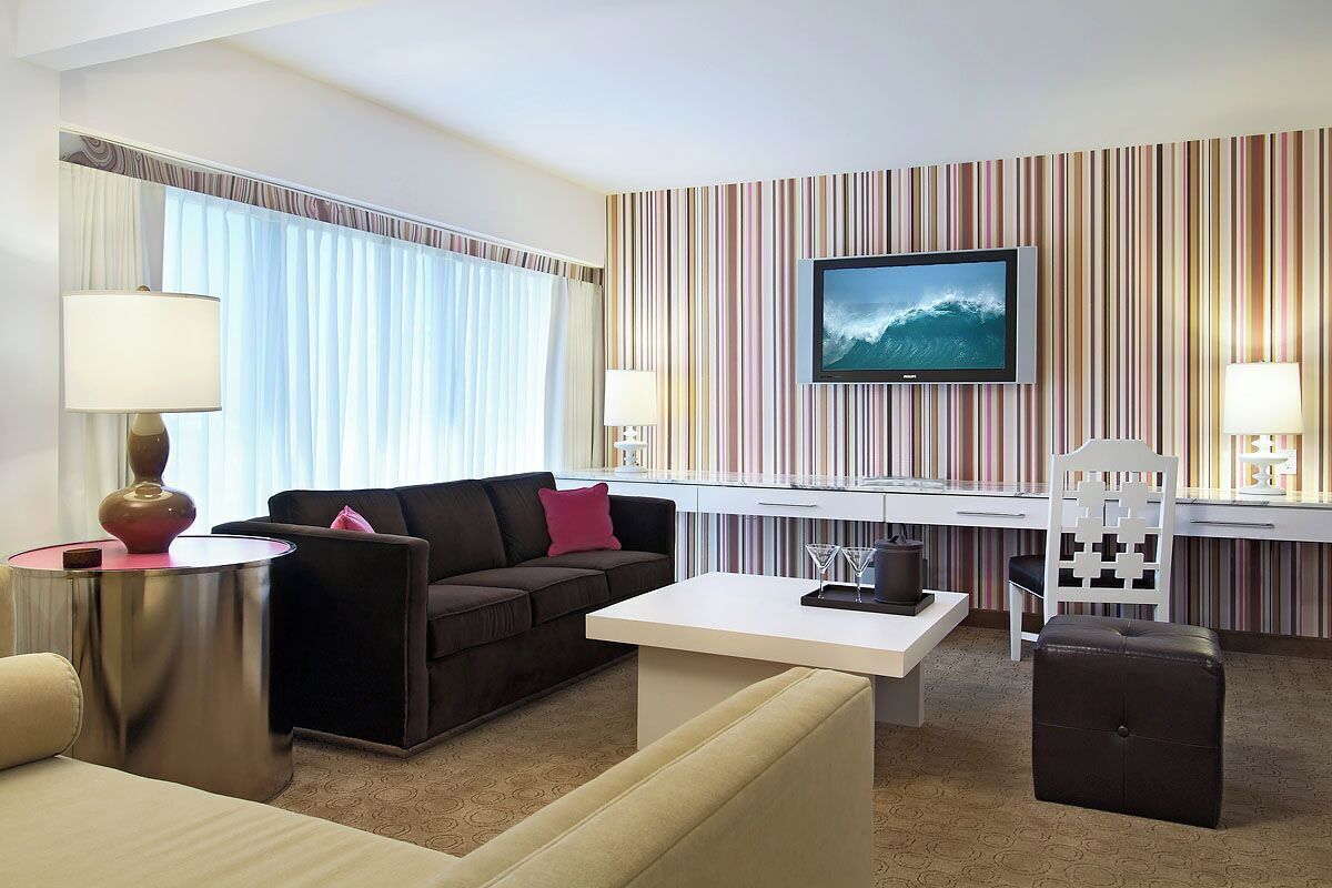 A hotel room with a sofa, a coffee table, a TV, a desk, and a chair.