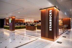 A Starbucks coffee shop with a modern design, featuring a counter, seating area, and a menu display.